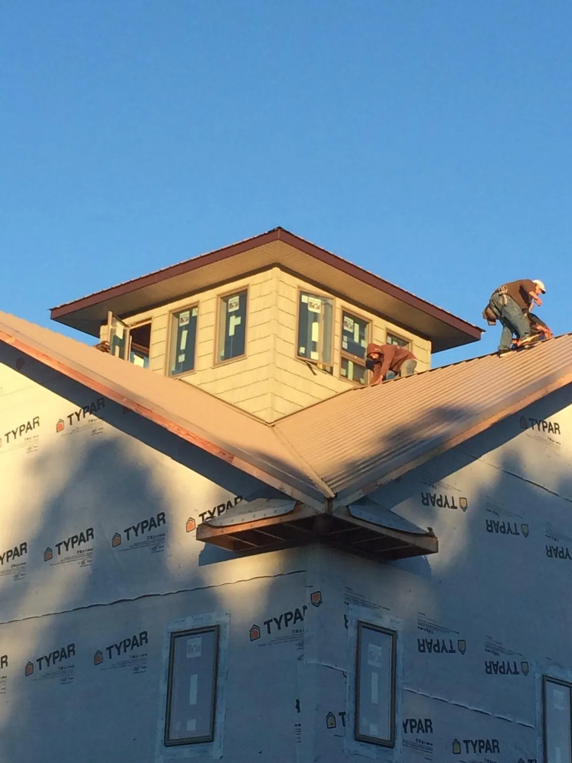 Roofers working around a rooftop cupola on a new metal roof at sunset — Roof Waterproofing in Willingboro by Roofing Brothers